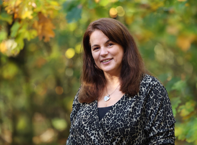Annemiek kijkt naar de camera in het bos